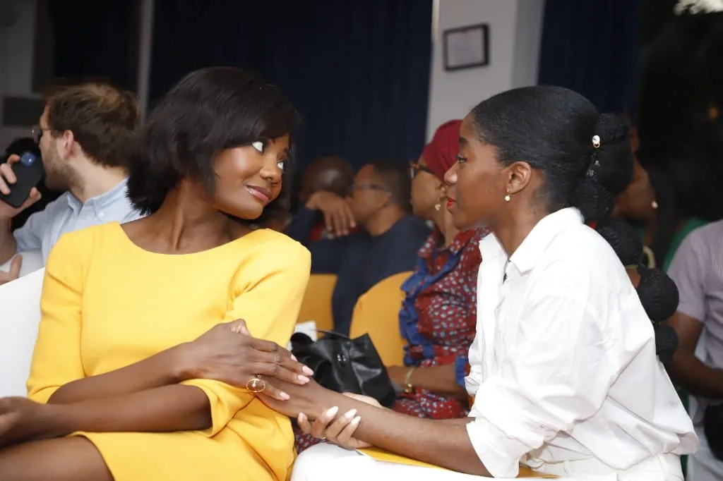 Two women in conversation at an event, a moment of listening and closeness, care anchored in community spaces.
